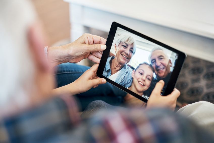 Senior mit Tablet beim Skypen mit der Familie