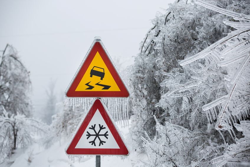 Zwei Verkehrsschilder Vorsicht Glätte in verschneiter Landschaft