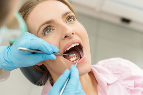 Frau mit offenem Mund bei der Zahnarztbehandlung