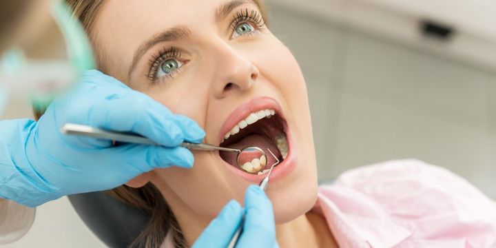Frau mit offenem Mund bei der Zahnarztbehandlung