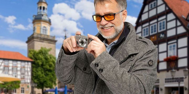 Mann mit Spezialbrille macht Fotos in einer Altstadt