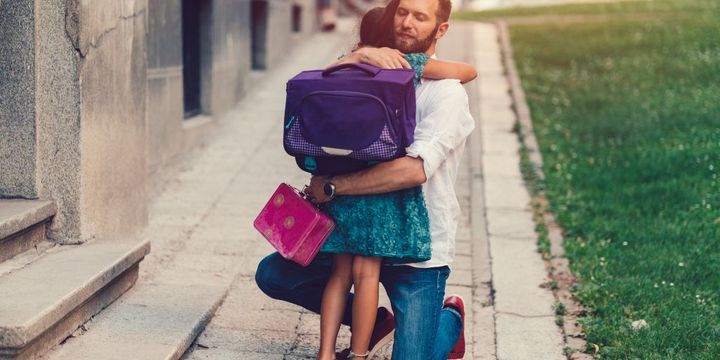 Vater holt Tochter von der Schule ab und umarmt sie