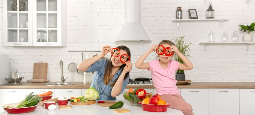Mutter und Tochter kochen gemeinsam und spielen mit Paprika