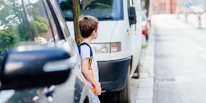 Kind zwischen Autos überquert Straße