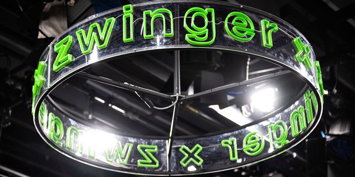Grün leuchtender Schriftzug zwinger x ringförmig angebracht auf einem durchsichtigen Ring, aufgehängt an der Bühnendecke des Zwingers