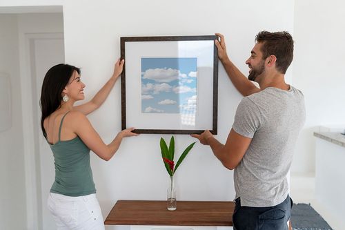 Paar hängt Bild an die Wand