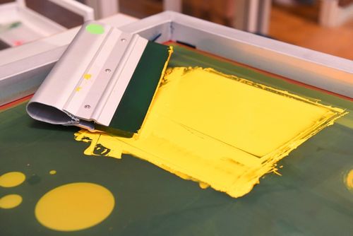 In der Druckwerkstatt: ein Sieb mit gelber Farbe