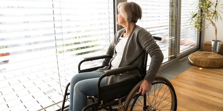 Seniorin im Rollstuhl schaut aus dem Fenster