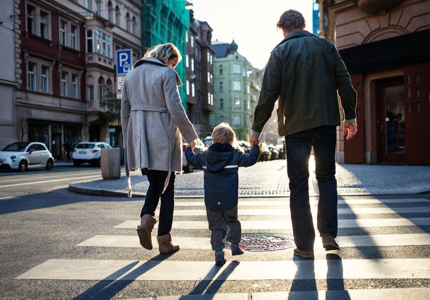 Eltern überqueren mit kleinem Kind an der Hand die Straße