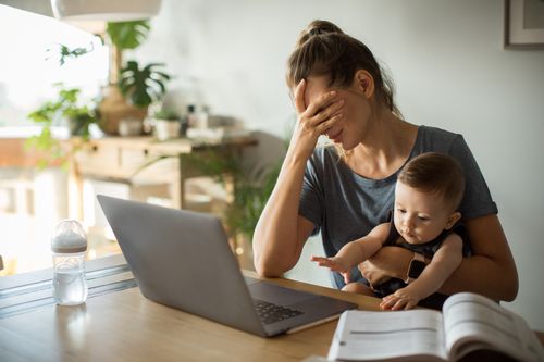 Frau mit Baby am Laptop ist müde
