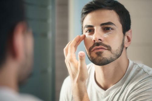 Mann vorm Spiegel bei der Gesichtspflege