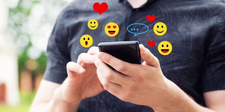 Mann tippt auf seinem Smartphones Emojis ein