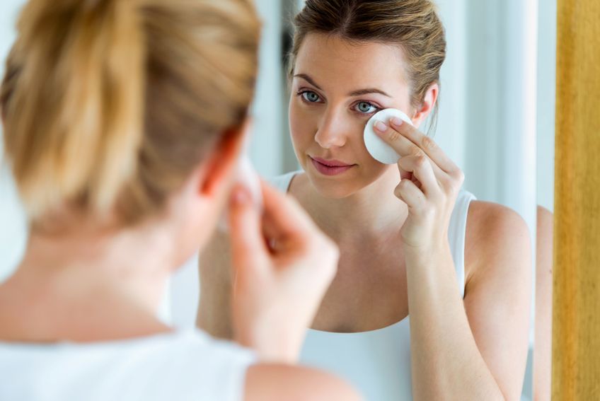 Frau vor dem Spiegel entfernt Make-up