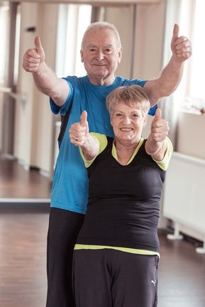 Zwei Senioren im Fitnessstudio, die das Daumen-Hoch Zeichen geben