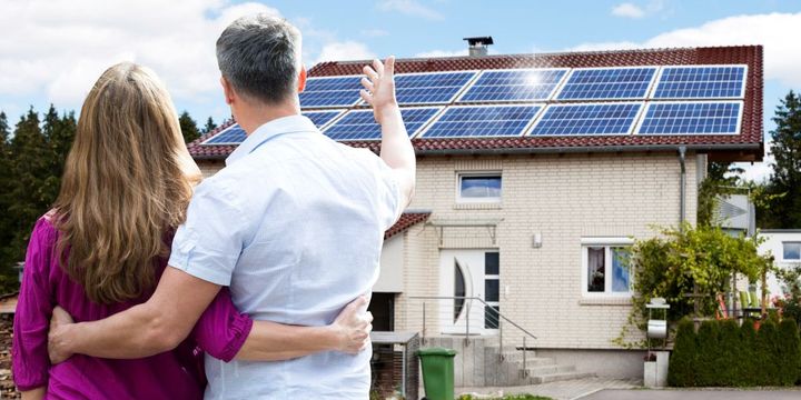 Mann zeigt seiner Frau die neue Photovoltaik-Anlage auf dem Dach