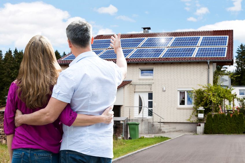 Mann zeigt seiner Frau die neue Photovoltaik-Anlage auf dem Dach