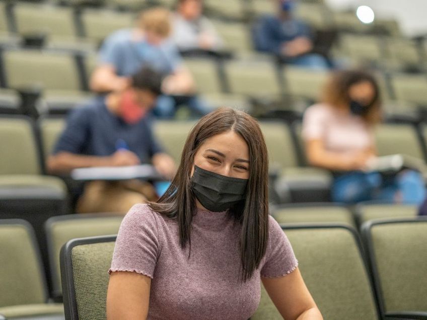 Studentin mit Maske im Hörsaal