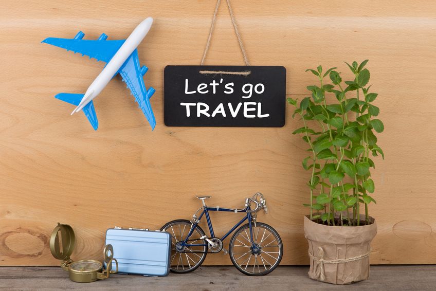 Konzeptbild Urlaub mit Flugzeug, Fahrrad, Koffer und Kompass