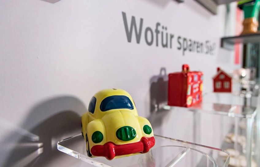 Eine Ausstellungsimpression des Wirtschaftsmuseums Ravensburg mit kleinen Gegenständen wie ein gelbes Auto, ein rotes Haus und ein roter Koffer.