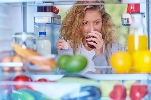 Frau riecht an Essen im Kühlschrank