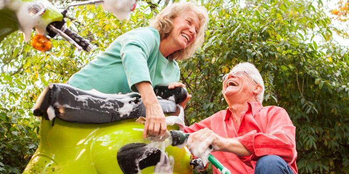 Älteres Paar wäscht lachend das Moped