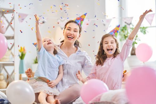 Mutter mit Töchtern feiert mit Konfetti und Luftballons