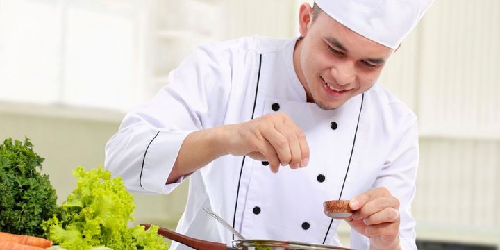 Auszubildender zum Koch bereitet Essen zu