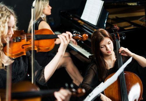Drei Musikerinnen spielen in einem klassischen Orchester