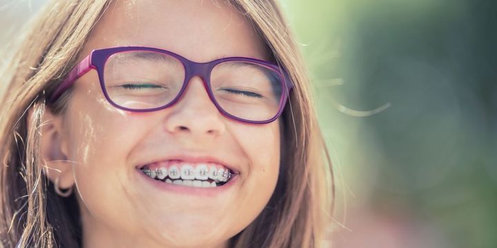 Lachendes Mädchen mit Zahnspange und Brille