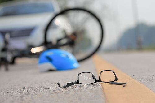 Brille, Fahrradhelm und Fahrrad auf der Straße nach einem Unfall mit einem Auto