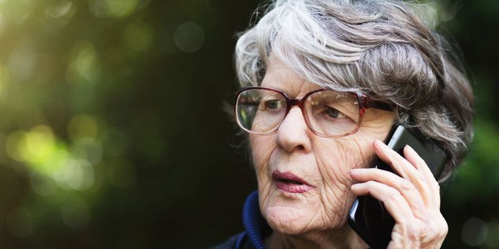 Seniorin besorgt am Telefon im Freien