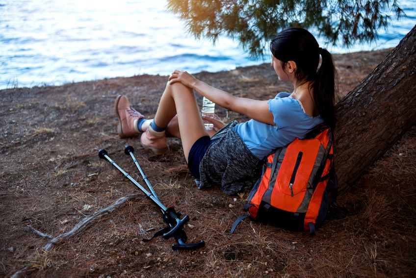 Junge Frau mit Hörgerät macht Pause beim Wandern an einem See