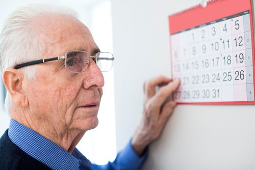 Senior mit Demenz schaut auf Terminkalender