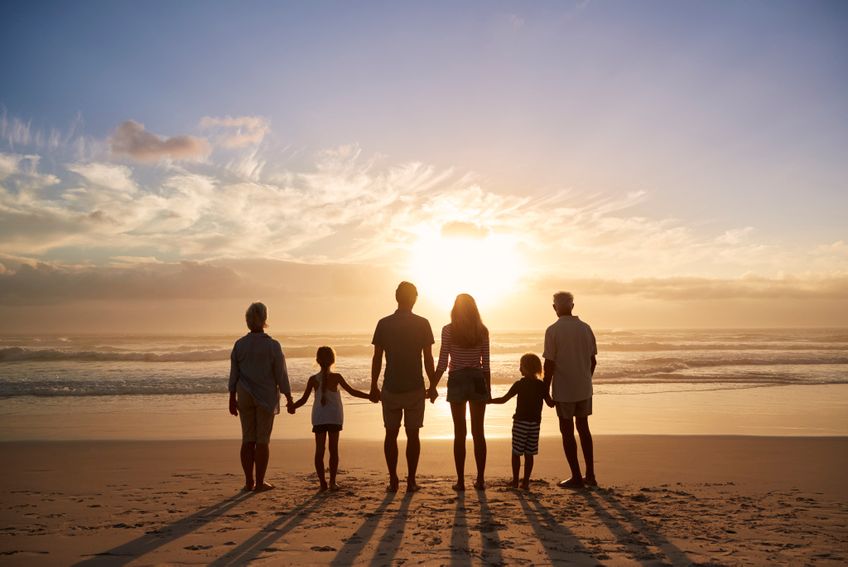 Familie am Strand betrachtet Sonenenuntergang