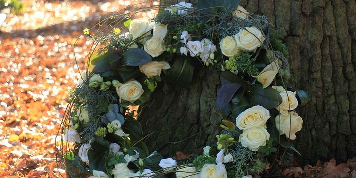 Baumgrab mit Blumenkranz im Bestattungswald