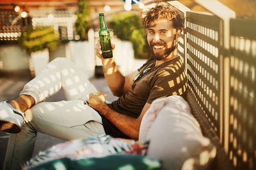 Mann mit Bier auf dem Balkon