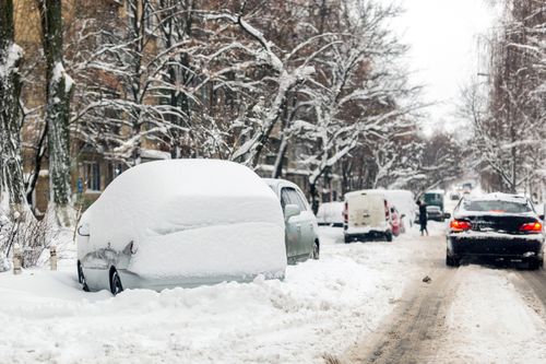 Schneebedeckte Straße mit parkenden Autos