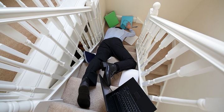 Mann im Home Office ist mit Laptop und Unterlagen die Treppe runtergefallen