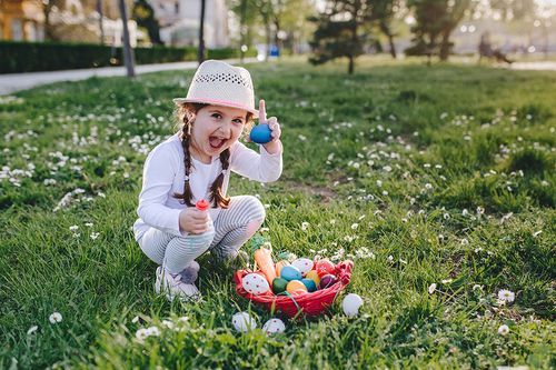 Mädchen freut sich über Ei bei der Ostereiersuche