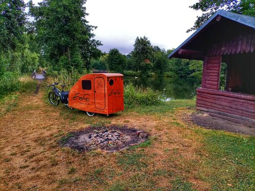 Fahrrad-Camper vor einer Hütte und Grillplatz