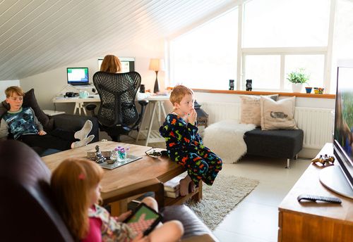Kinder schauen fern, während Mutter im Home Office arbeitet
