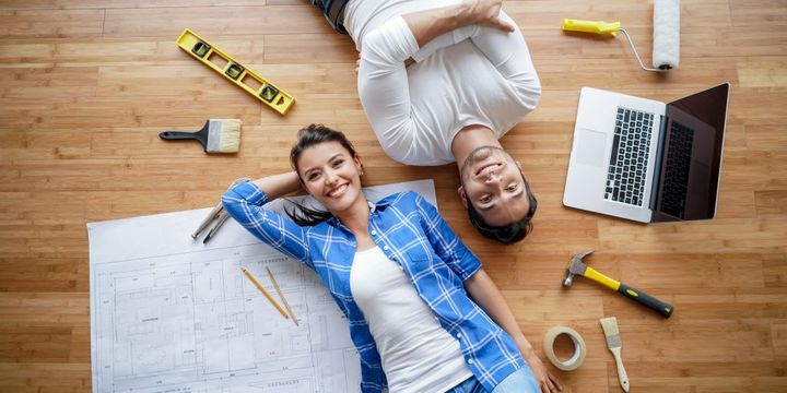 Junges Paar auf dem Boden liegend plant ein Bauprojekt