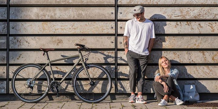 Paar lehnt an Wand mit Fahrrad daneben
