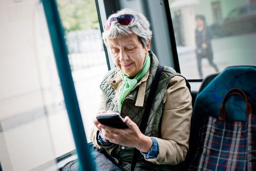 Seniorin im Bus mit Smartphone