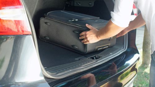 Mann lädt Reisegepäck in den Kofferraum