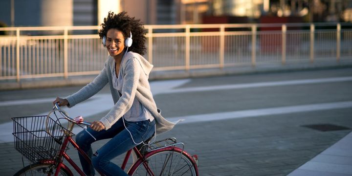 Junge Frau mit Kopfhörern auf dem Fahrrad