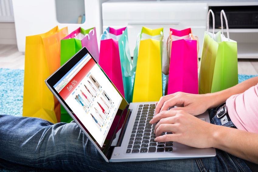 Online Shopping am Laptop dahiter bunte Einkaufstüten