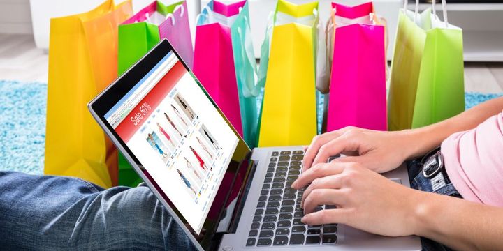 Online Shopping am Laptop dahiter bunte Einkaufstüten