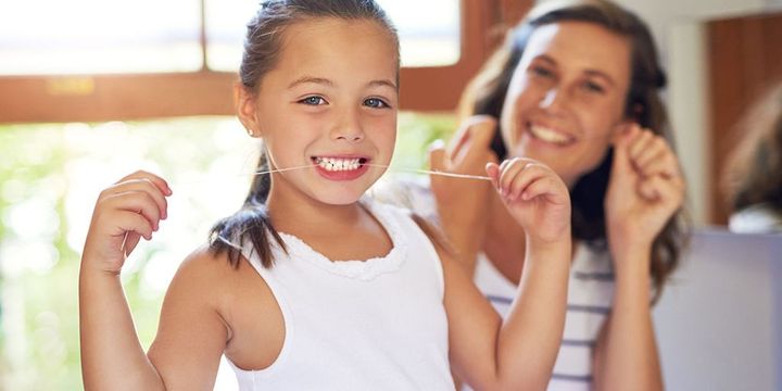 Tochter und Mutter benutzen Zahnseide