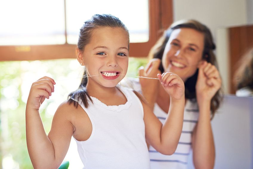 Tochter und Mutter benutzen Zahnseide